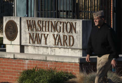 FILE - In this Sept. 19, 2013 file photo. military personnel walks past an entrance to the Washington Navy Yard in Washington. An official says shots have been reported in a building on the Washington Navy Yard campus.   (AP Photo/Charles Dharapak, File)
