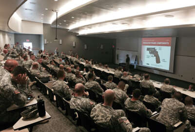 In this Aug. 3, 2015 photo provided by Charles Hiltunen, members of the Indiana Nation Guard undergo National Rifle Association firearm training in the auditorium of the Johnson County Armory in Franklin, Ind. Indiana Republican Gov. Mike Pence has tapped the NRA to train state National Guard members who wish to carry concealed and privately-owned handguns while on-duty. (Charles Hiltunen via AP)