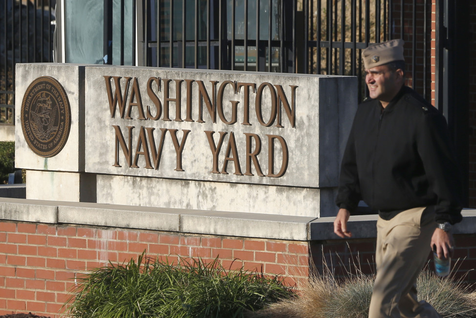 FILE - In this Sept. 19, 2013 file photo, military personnel walks past an entrance to the Washington Navy Yard in Washington. Two years after the shooting at the Washington Navy Yard, families whose loved ones died are filing multimillion dollar lawsuits against companies they say could have prevented it from happening.  (AP Photo/Charles Dharapak, File)