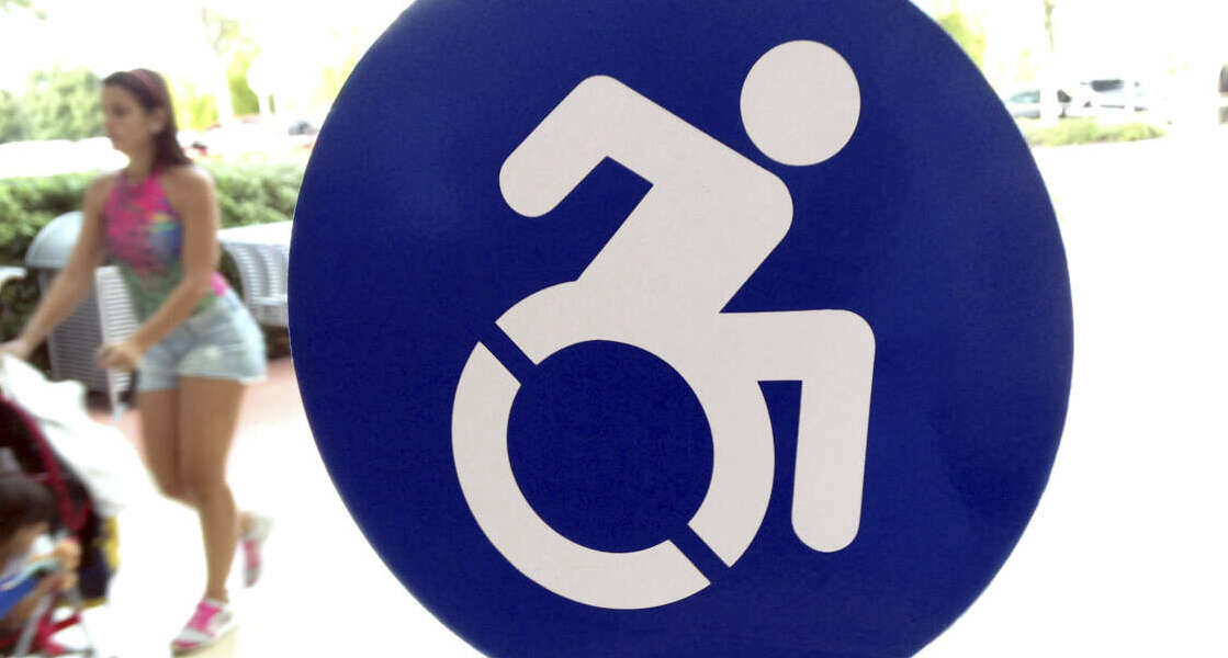 In this Wednesday, Oct. 7, 2015 photo, a modernized handicapped sign is affixed to a door at the The Mall at Millenia in Orlando, Fla. Advocates want to replace the familiar image of a stick figure in a wheelchair with this action-oriented logo to emphasize ability, not disability.  (AP Photo/Bill Sikes)
