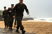 U.S. Marines walk on the beach at Waimea Bay near Haleiwa, Hawaii, where two military helicopters crashed into the ocean about 2 miles offshore, Friday, Jan. 15, 2106. The helicopters carrying 12 crew members collided off the Hawaiian island of Oahu during a nighttime training mission, and rescuers are searching a debris field in choppy waters Friday, military officials said. (Mariana Keller via AP Photo)