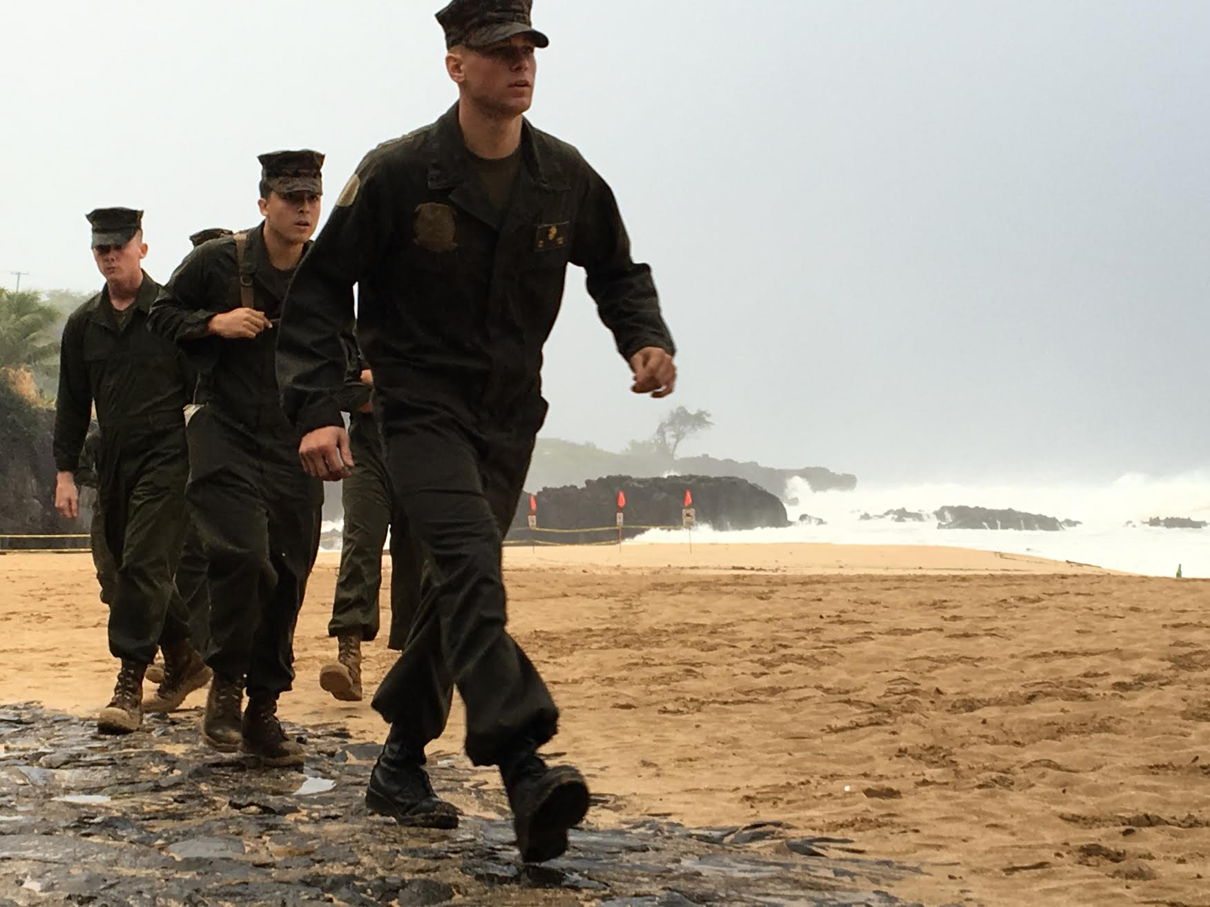 U.S. Marines walk on the beach at Waimea Bay near Haleiwa, Hawaii, where two military helicopters crashed into the ocean about 2 miles offshore, Friday, Jan. 15, 2106. The helicopters carrying 12 crew members collided off the Hawaiian island of Oahu during a nighttime training mission, and rescuers are searching a debris field in choppy waters Friday, military officials said. (Mariana Keller via AP Photo)