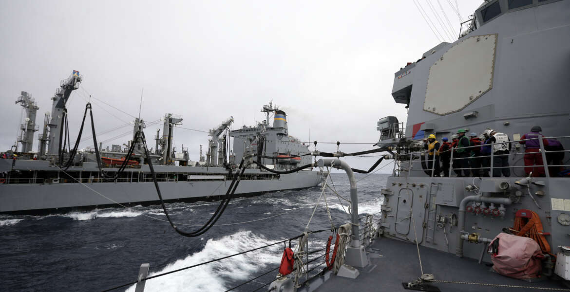 Fuel lines connect the USS William P. Lawrence guided missile destroyer, right, with a tanker during a refueling at sea Wednesday, Jan. 20, 2016, in waters off  Coronado, Calif. The U.S. Navy is launching a carrier strike group to be powered partly by biofuel, calling it a milestone toward easing the military's reliance on foreign oil. (AP Photo/Gregory Bull)