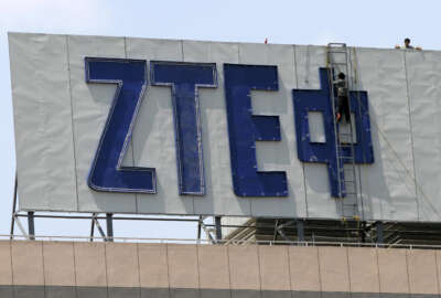 In this April 18, 2007 photo, workers install the logo for ZTE, a leading Chinese communications company, on top of an office building in Nanjing in eastern China's Jiangsu province. Washington has imposed restrictions on the ability of one of China's biggest telecoms equipment makers, ZTE Corp., to use American components after concluding the state-owned company improperly exported U.S. technology to Iran. Sanctions that took effect Tuesday, March 8, 2016, were imposed after ZTE was found to be 