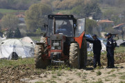 Greek police officers speak with Lazaros Oulis, farmer and owner of fields near the makeshift refugee camp at the northern Greek border point of Idomeni, Greece, Thursday, March 31, 2016. Oulis, tried to plough his land on Thursday, driving the tractor near the  tents and people.(AP Photo/Darko Vojinovic)