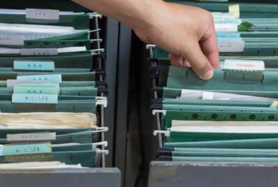 Hand holding top secret file in filing cabinet