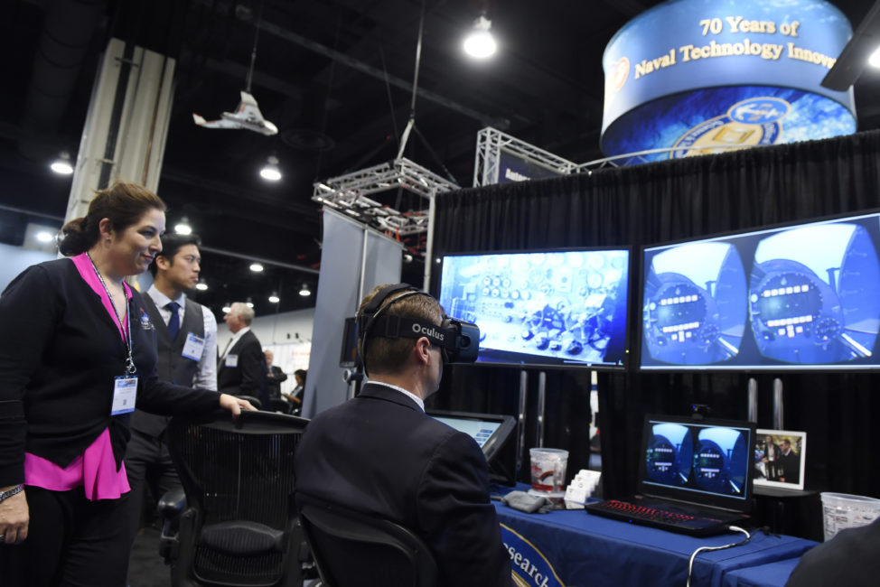 NATIONAL HARBOR, Md. (May 16, 2016) Lauren Burnette, from Space and Naval Warfare Systems Command (SPAWAR) Systems Center Pacific, explains the Battlespace Exploitation of Mixed Reality (BEMR) Lab demo to a visitor at the Office of Naval Research (ONR) exhibit during the 2016 Sea-Air-Space Exposition. BEMR is designed to showcase and demonstrate cutting edge low cost commercial mixed reality, virtual reality and augmented reality technologies and to provide a facility where warfighters, researchers, government, industry and academia can collaborate. (U.S. Navy photo by John F. Williams/Released) 