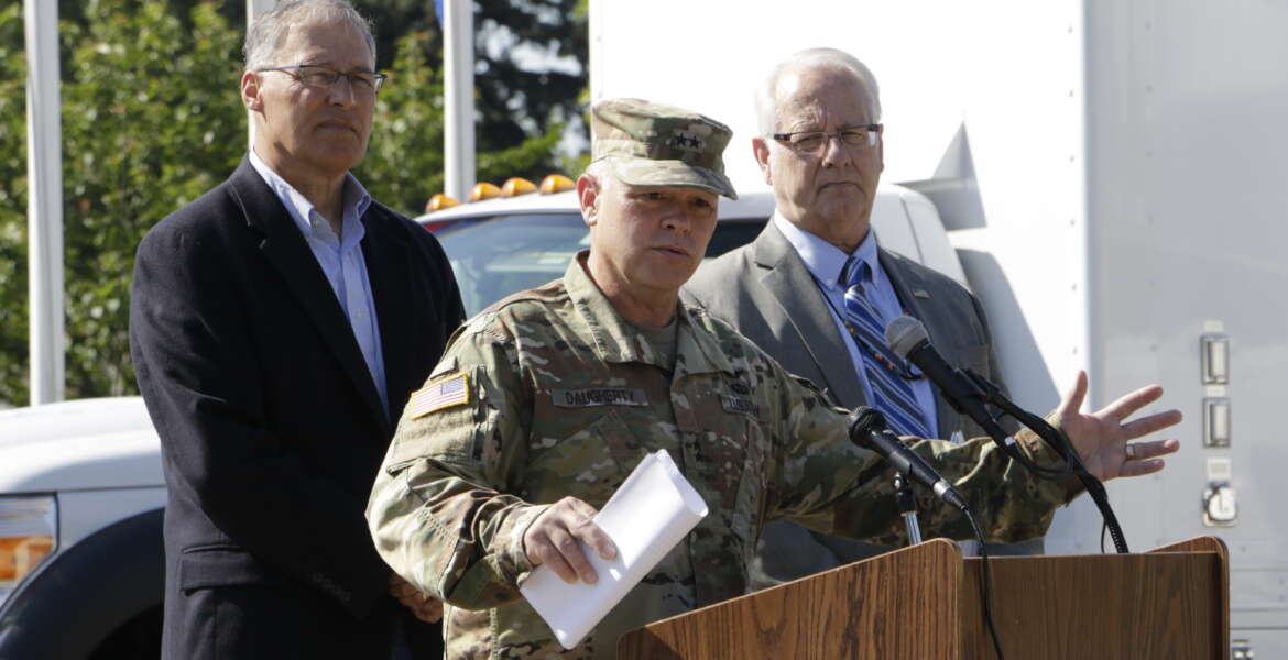 Major General Bret Daugherty, commander of the Washington National Guard, speaks to the media as Washington Gov. Jay Inslee, left, and FEMA Region X Administrator Ken Murphy look on, Tuesday, June 7, 2016, at Camp Murray, Wash.  Washington is participating in a four-day earthquake and tsunami readiness drill in the Pacific Northwest called Cascadia Rising. (AP Photo/Rachel La Corte)
