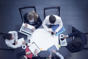 Business workplace with people, cup of coffee, digital tablet, smartphone, papers and various office objects on table