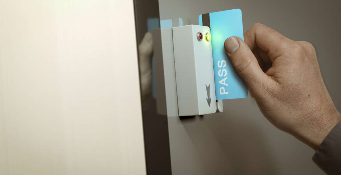 Hand with blue pass card unlocking access to a restricted area. Concept image for security and data protection.