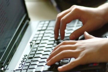 Hands typing on laptop keyboard.