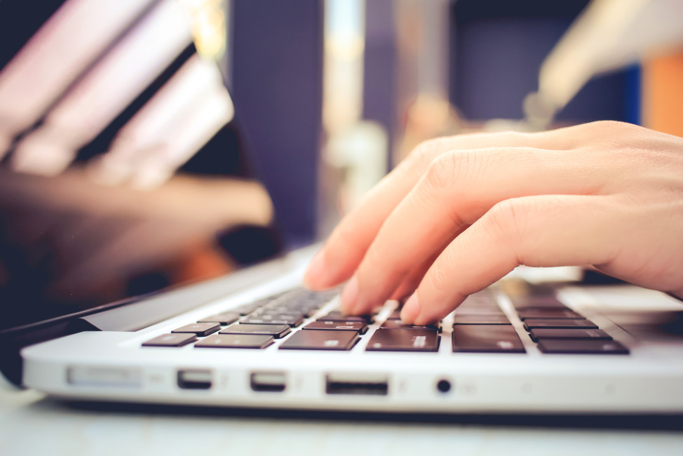 Female hands typing on keyboard of laptop