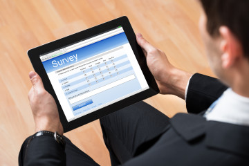 Close-up Of Businessman Looking At Blank Online Survey Form On Digital Tablet