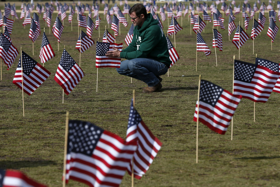 Navy veteran Jeff Hensley of Dallas, Texas, now with Iraq and Afghanistan Veterans of America (IAVA), joins others in placing 1,892 flags representing veteran and service members who have died by suicide to date in 2014, Thursday, March 27, 2014, on the National Mall in Washington. The event also marked the introduction of The Suicide Prevention for America's Veterans Act by Sen. John Walsh, D-Mont., which calls for greater access to mental health care. (AP Photo/Charles Dharapak)