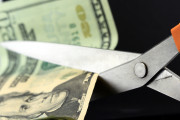 Scissors cutting into US dollars business concept for cost cutting