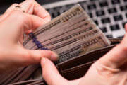 Close up of female hands counting US dollar banknotes at the table in front a laptop computer. Woman accountant with money and notebook.