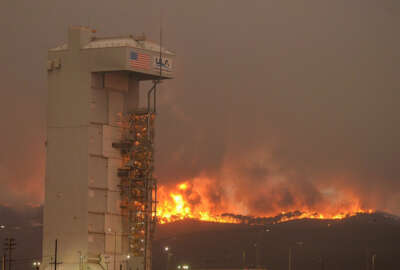 In this Monday, Sept. 19, 2016 photo provided by the Santa Barbara County Fire Department, a fire burns several miles behind Space Launch Complex-3, housing the Atlas V rocket & WorldView 4 satellite, at Vandenberg Air Force Base, Calif. Crews are working to surround the wildfire at the central California Air Force base that forced the postponement of a weekend satellite launch. The blaze has expanded to the south as it grew to more than 16 square miles.   (Mike Eliason/Santa Barbara County Fire Department via AP)