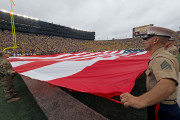 U.S. Army and Marines service members and veterans hold a large American flag over the field during the playing of the national anthem, before an NCAA college football game against Central Florida at Michigan Stadium in Ann Arbor, Mich., Saturday, Sept. 10, 2016. (AP Photo/Tony Ding)