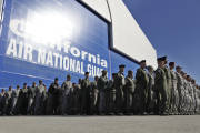 FILE - In this Nov. 30, 2011 file photo, California Army National Guard soldiers watch the arrival of the body of soldier Sean Walsh, who died on Nov. 16 during a combat operation in Afghanistan, at Moffett Federal Airfield in Mountain View, Calif. Nearly 10,000 California National Guard soldiers have been ordered to repay huge enlistment bonuses a decade after signing up to serve in Iraq and Afghanistan, the Los Angeles Times reported Saturday, Oct. 22, 2016. (AP Photo/Paul Sakuma, File)