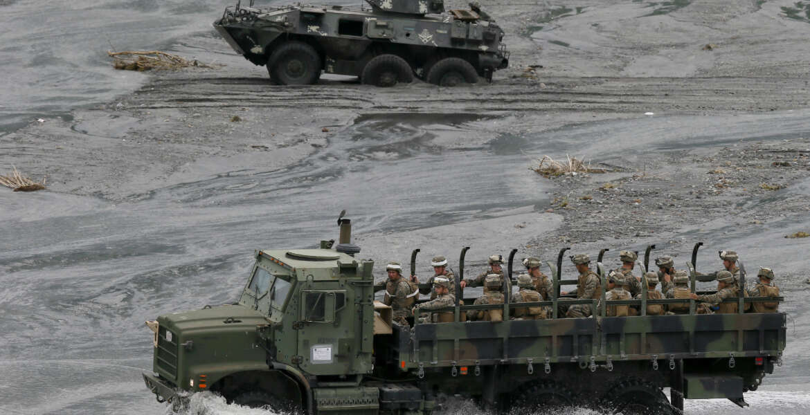 A military truck, foreground, carrying U.S. Marines from the 3rd Marine Expeditionary Brigade forces drives past a Philippine Marine APC (Armored Personnel Carrier) which got stuck in the sandy portion of a riverbed as they take part in a live-fire amphibious landing exercise dubbed PHIBLEX Monday, Oct. 10, 2016 in Crow Valley in Capas township, Tarlac province, north of Manila, Philippines. The combat drill, however, maybe the last under President Rodrigo Duterte, who has opposed the war games partly because they may upset China and because of his disgust over U.S. criticisms of his bloody anti-drug campaign. (AP Photo/Bullit Marquez)