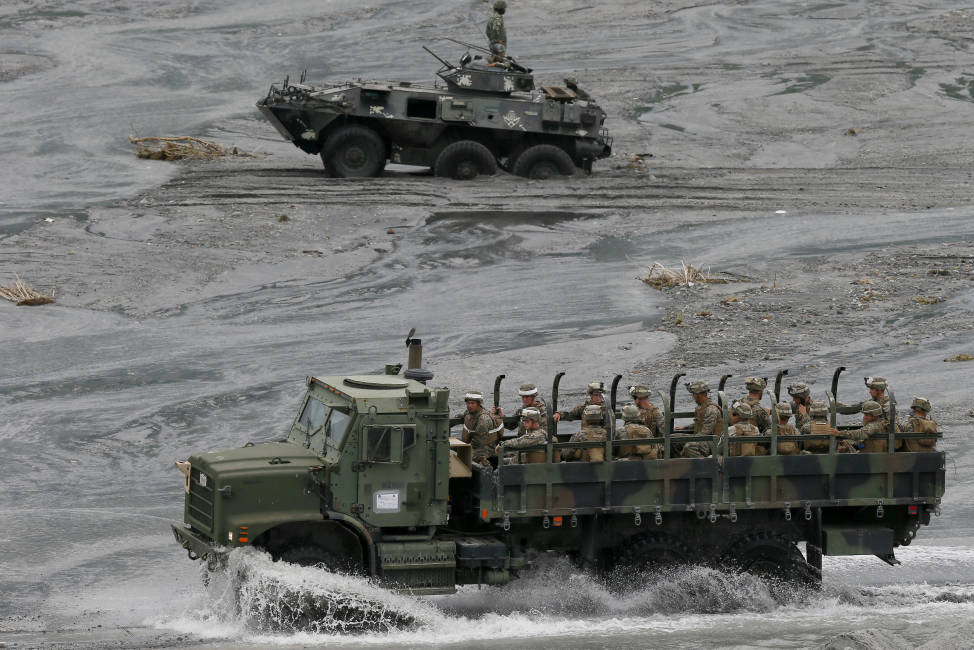 A military truck, foreground, carrying U.S. Marines from the 3rd Marine Expeditionary Brigade forces drives past a Philippine Marine APC (Armored Personnel Carrier) which got stuck in the sandy portion of a riverbed as they take part in a live-fire amphibious landing exercise dubbed PHIBLEX Monday, Oct. 10, 2016 in Crow Valley in Capas township, Tarlac province, north of Manila, Philippines. The combat drill, however, maybe the last under President Rodrigo Duterte, who has opposed the war games partly because they may upset China and because of his disgust over U.S. criticisms of his bloody anti-drug campaign. (AP Photo/Bullit Marquez)