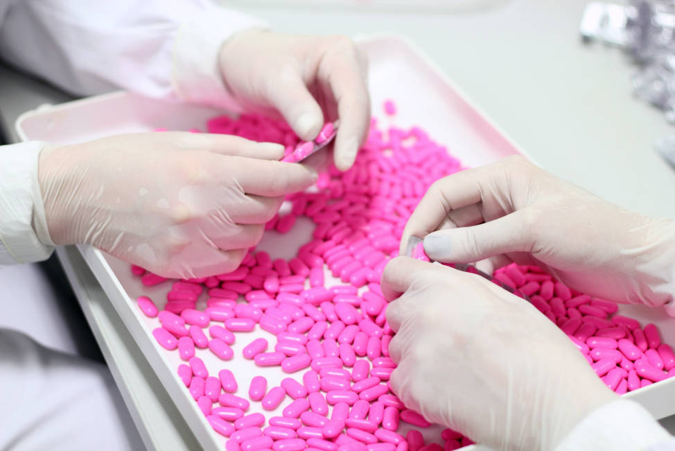 Laboratory technicians inspecting the quality of pills at a pharmaceutical plant.