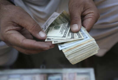 In this Monday, Dec. 5, 2016 photo, an Afghan money changer counts U.S. dollar banknotes at a money exchange market in Kabul, Afghanistan. Afghans are increasingly uncertain about their future, less confident in their government and more pessimistic than before on issues such as security, corruption, and rising unemployment, according to the annual survey by the San Francisco-based Asia Foundation released on Wednesday, Dec. 7, 2016. (AP Photo/Rahmat Gul)