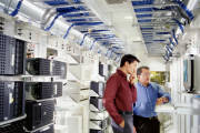 Two businessmen using computer in server room