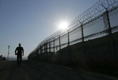 In this June 22, 2016 photo, a Border Patrol agent walks along a border structure in San Diego. Only about one of every three applicants passes CBP's polygraph, which is barely half the pass rate among law enforcement agencies that provided data to The Associated Press under open-records law requests. (AP Photo/Gregory Bull)