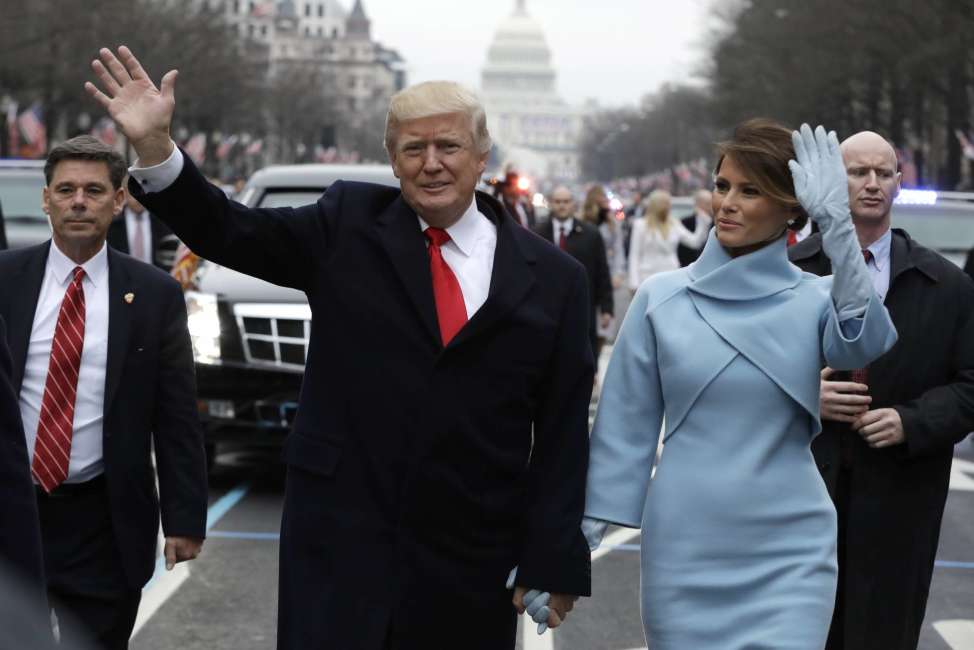 President Donald Trump waves as he walks with first lady Melania Trump during the inauguration parade on Pennsylvania Avenue in Washington, Friday, Jan. 20, 2016. (AP Photo/Evan Vucci, Pool)