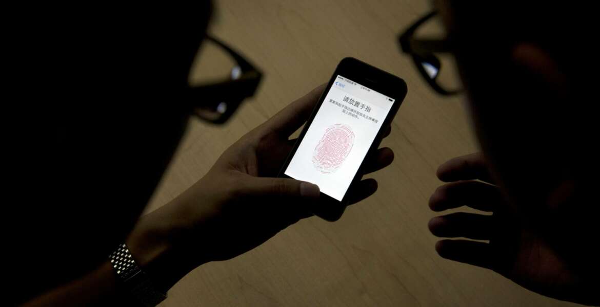 CORRECTS TO U.S. CUSTOMS AND BORDER PROTECTION, NOT PATROL - FILE - In this Sept. 11, 2013, file photo, an Apple employee, right, instructs a journalist on the use of the fingerprint scanner technology built into the company's iPhone 5S during a media event in Beijing. Watchdog groups that keep tabs on digital privacy rights are concerned that U.S. Customs and Border Protection agents are searching the phones and other digital devices of international travelers at border checkpoints in U.S. airports. The American Civil Liberties Union and the Electronic Frontier Foundation say complaints of such searches have spiked recently. (AP Photo/Ng Han Guan, File)