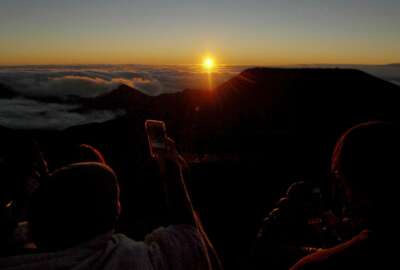 People watch as the sun rises in front of the summit of Haleakala volcano in Haleakala National Park on Hawaii's island of Maui, Sunday, Jan. 22, 2017. Reservations can be made up to two months in advance at the website recreation.gov. (AP Photo/Caleb Jones)
