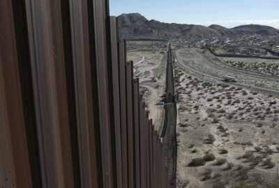 FILE - This Jan. 25, 2017, file photo shows a truck driving near the Mexico-US border fence, on the Mexican side, separating the towns of Anapra, Mexico and Sunland Park, New Mexico. President Donald Trump will face many obstacles in building his “big, beautiful wall” on the U.S.-Mexico border, including how to pay for it and how to contend with unfavorable geography and the legal battles ahead.  (AP Photo/Christian Torres, File)
