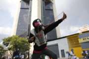 An opponent of President Nicolas Maduro aims his slingshot during protests as security forces block protesters from reaching the national ombudsman office in Caracas, Venezuela, Wednesday, April 26, 2017. Hundreds of thousands of Venezuelans have flooded the streets over the last month to demand an end to Maduro's presidency. (AP Photo/Ariana Cubillos)