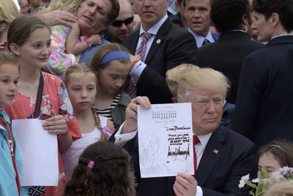 President Donald Trump shows the letter he wrote to a service member during the annual White House Easter Egg Roll on the South Lawn of the White House in Washington, Monday, April 17, 2017. (AP Photo/Susan Walsh)