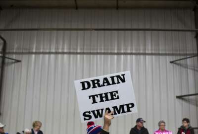 FILE - In this Oct. 27, 2016 file photo, supporters of then-Republican presidential candidate Donald Trump hold signs during a campaign rally in Springfield, Ohio. The Trump administration insists that “drain the swamp” is more than a throwaway catchphrase, yet in the last three months, the White House has become less transparent, hired scores of special interest players, raised money from lobbyists and taken no concrete steps to address campaign finance.  (AP Photo/ Evan Vucci, file)