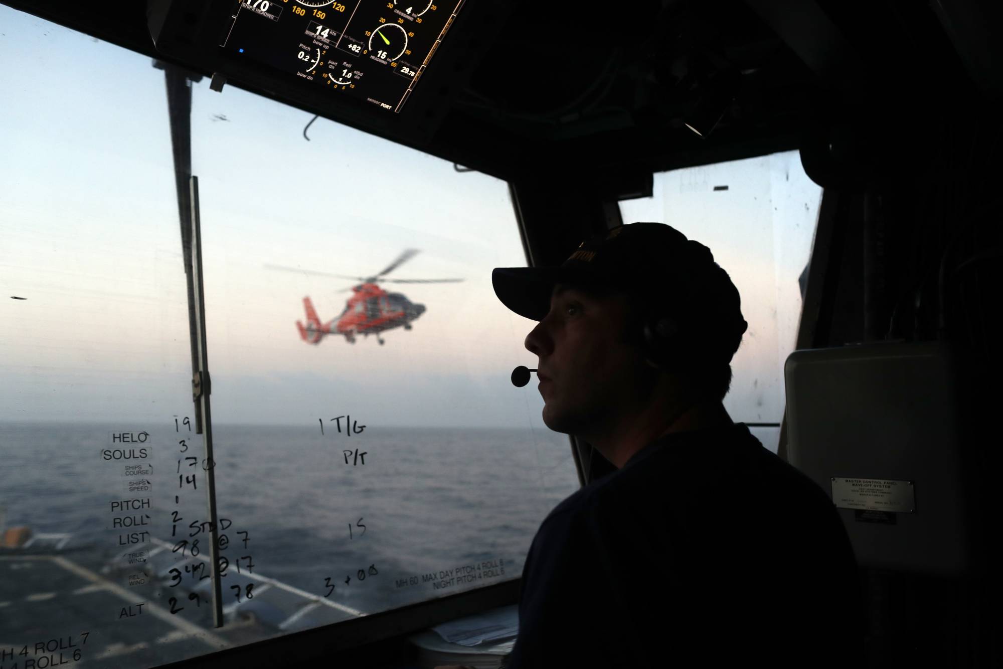 In this March 2, 2017 photo, an unidentified U.S. Coast Guardsman communicates with the pilot of a helicopter during take-off and landing exercises on the U.S. Coast Guard cutter Stratton in the eastern Pacific Ocean. For its drug interdiction operations, the Coast Guard is bringing more intelligence and technology to bear. Deep within the Stratton, specialists crunch data from radar, infrared video,helicopter sorties as well as other available sources. (AP Photo/Dario Lopez-Mills)