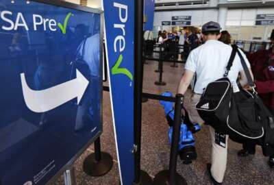 In this Monday, June 27, 2016, photo, a passenger passes by a sign for the Transportation Security Administration's TSA Precheck line in Terminal A at Logan Airport in Boston. By air or car, summer 2017 travel numbers are expected to rise over the previous year thanks to deals on airfares and stable gasoline prices. (AP Photo/Charles Krupa)