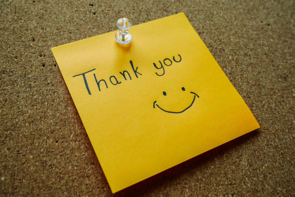 Writting "Thank you" on post it note for someoneWritting "Thank you" on post it note for someone