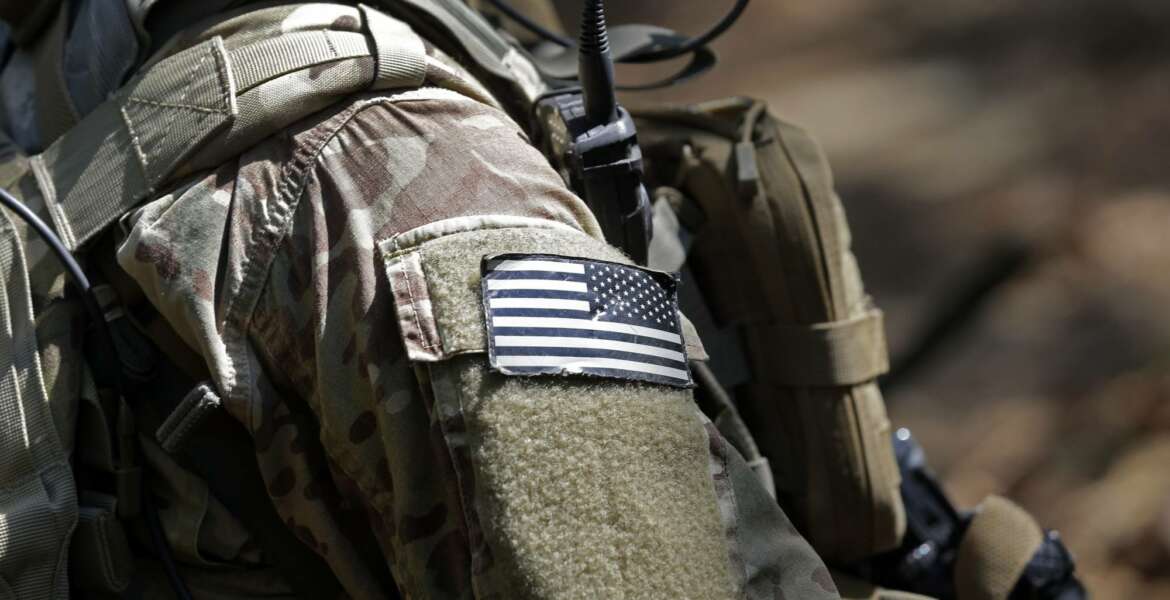 In this photo taken Friday, April 21, 2017 a United States flag patch adorns the uniform of a paratrooper with the 82nd Airborne Division's 3rd Brigade Combat Team during a training exercise at Fort Bragg, N.C. The Army is planning to triple the amount of bonuses it’s paying this year to more than $380 million in a bid to expand its ranks. The money includes new incentives to woo reluctant soldiers to re-enlist.  (AP Photo/Gerry Broome)