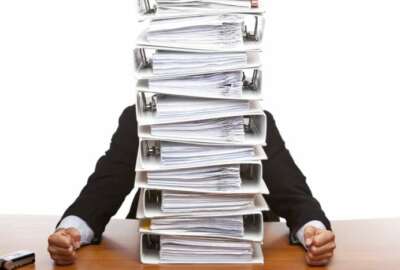 Businessman is frustrated, because of the huge documents he has to do. Isolated on white.