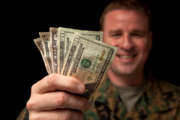 A happy military man holds money in his hands