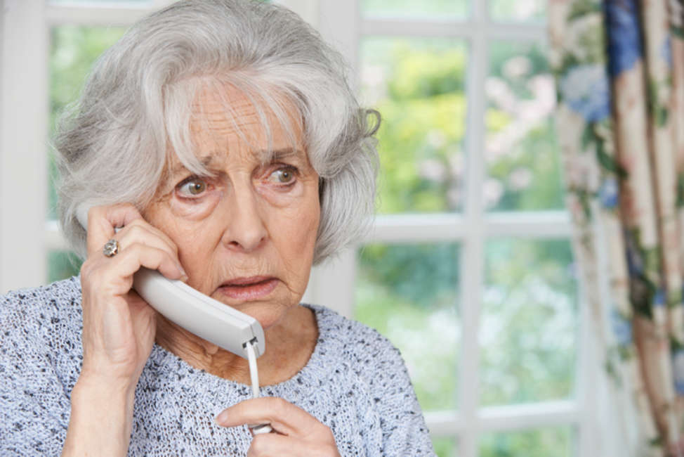 Worried Senior Woman Answering Telephone At Home