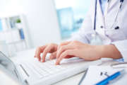 Close-up of hands of a nurse typing on laptop