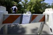 New Jersey State Park police block the entrance to Bulls Island state recreation area during the state government shutdown in Stockton, N.J. , Sunday, July 2, 2017. New Jersey's government shutdown dragged into a second day Sunday without a resolution to the stalemate between a defiant Republican Gov. Chris Christie and an unmoving Democratic Assembly Speaker Vincent Prieto. (Ed Murray/NJ Advance Media via AP)