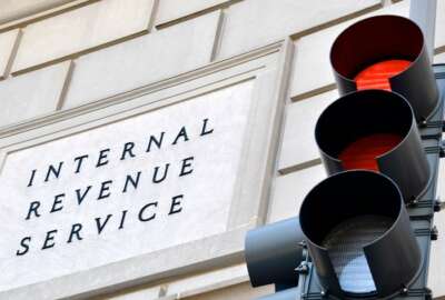 Internal Revenue Service sign with a traffic signal in the foreground indicating a red light.