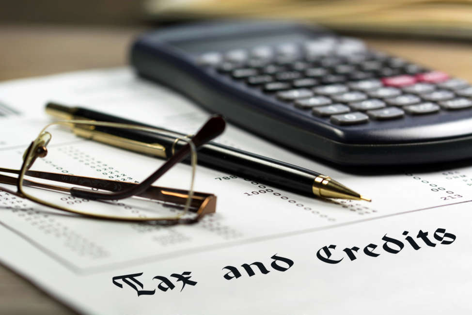 Tax and credits concept. Getting refund from the income tax return. Calculator, glasses and black pen on financial documents