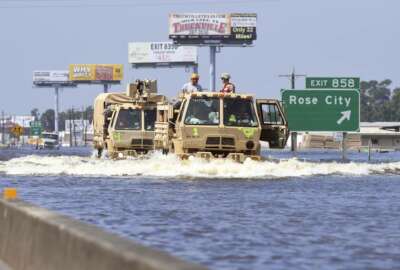 CORRECTS TO REMOVE REFERENCE OF FOOD CART- Military grade vehicles travel west on the east bound lanes of Interstate 10 in north Vidor, Texas, Thursday, Aug. 31, 2017. While several parts of the city are flooded, the northern side received extensive damage. (Guiseppe Barranco/The Beaumont Enterprise via AP)