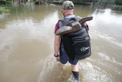 CORRECTS CREDIT - Danny Hannon carries his dry boots in his backpack as he goes to check his home in the aftermath of Harvey, Wednesday, Aug. 30, 2017 in Houston. Harvey's floodwaters started dropping across much of the Houston area, but many thousands of homes in and around the nation's fourth-largest city were still swamped and could stay that way for days or longer. (Melissa Phillip/Houston Chronicle via AP)