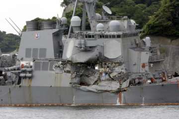 FILE - In this June 18, 2017, file photo, the damaged USS Fitzgerald is docked at the U.S. Naval base in Yokosuka, southwest of Tokyo, after colliding with Philippine-flagged container ship ACX Crystal off Japan.  On June 17, 2017, seven sailors died after a container ship collided with the USS Fitzgerald guided-missile destroyer off Japan. (AP Photo/Eugene Hoshiko, File)